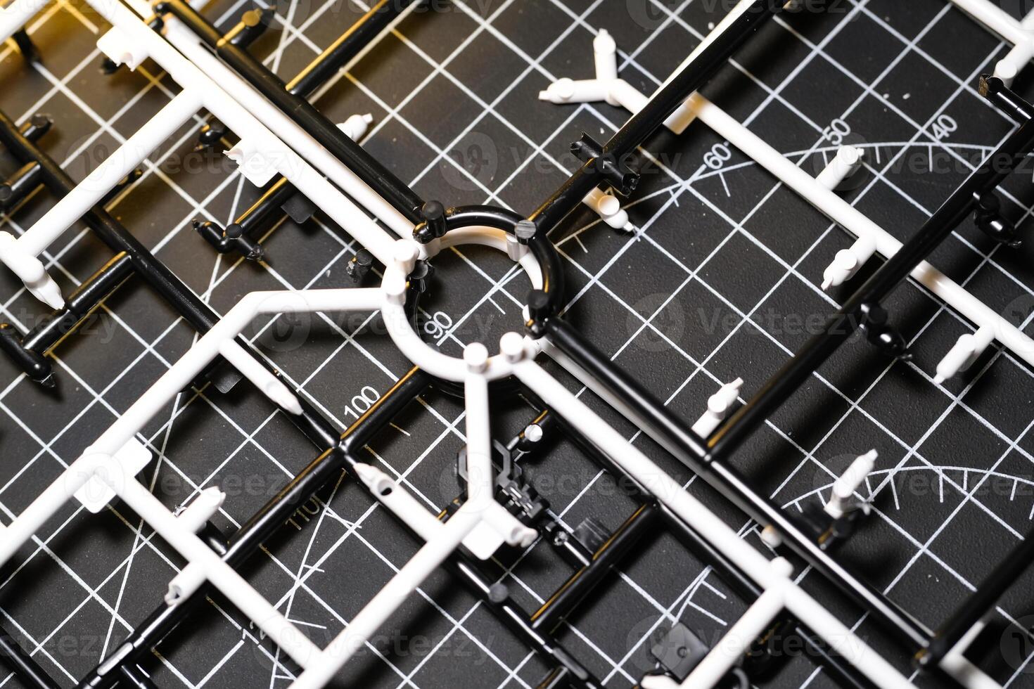 Plastic runner frames in black and white stacked on a cutting mat. Plastic model kit frames left over from cutting parts. Abstract Backgrounds. photo