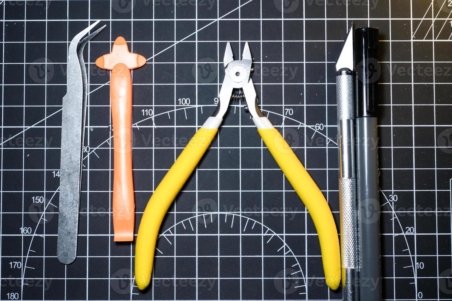 Set for building plastic model kits. Consisting of Nipper, Ink pen, cutting blade, plastic separator, and metal tweezer. Tools and equipment on black cutting mat. Toys and Model kits photo