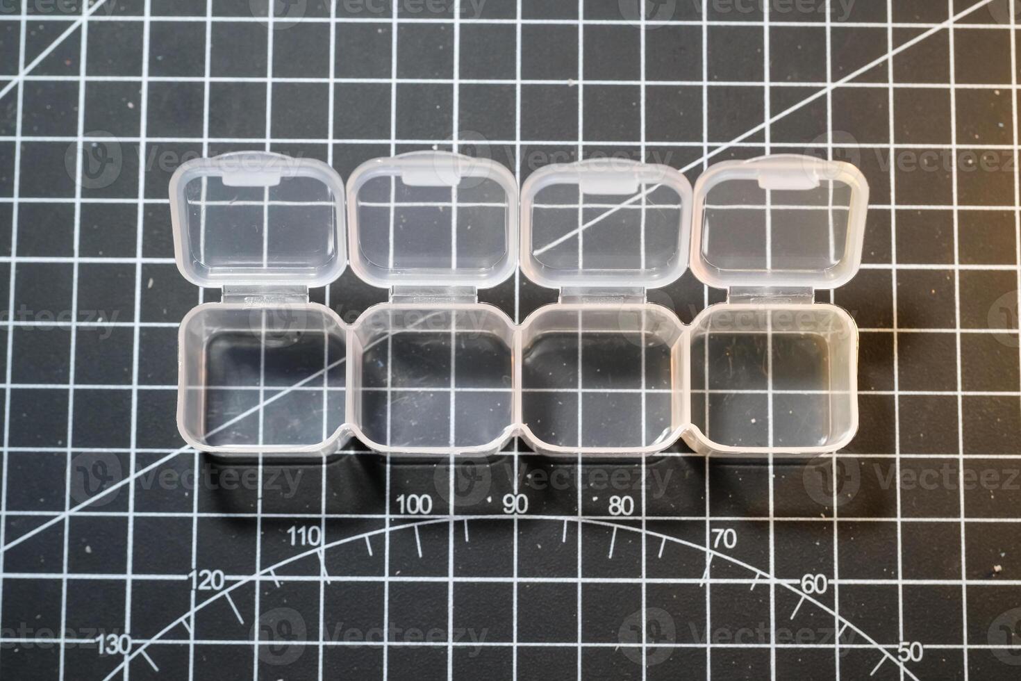 Mini container set on black striped cutting mat. Four small containers for storing tiny parts. Model kits and robotic build hobbies. Plastic equipments. Isolated objects on black photo