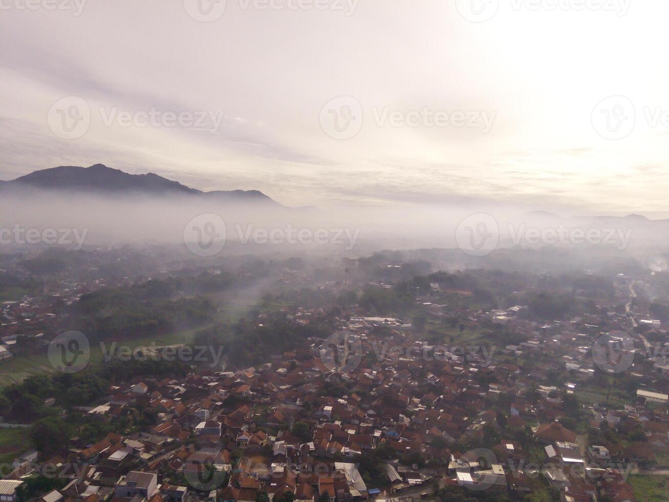 Bandung, Indonesia. Aerial Landscape view of foggy sky above mountains at dawn. High angle view of Mountain and cityscape in valley. Panorama of Highland in Bandung. photo