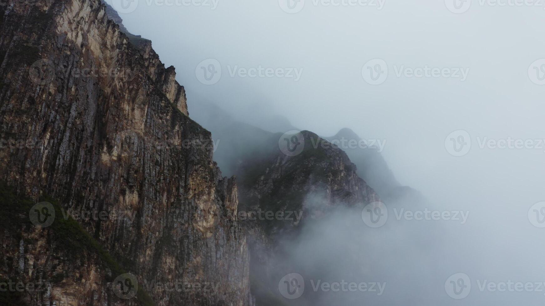 A mountain with fog and clouds in the sky photo