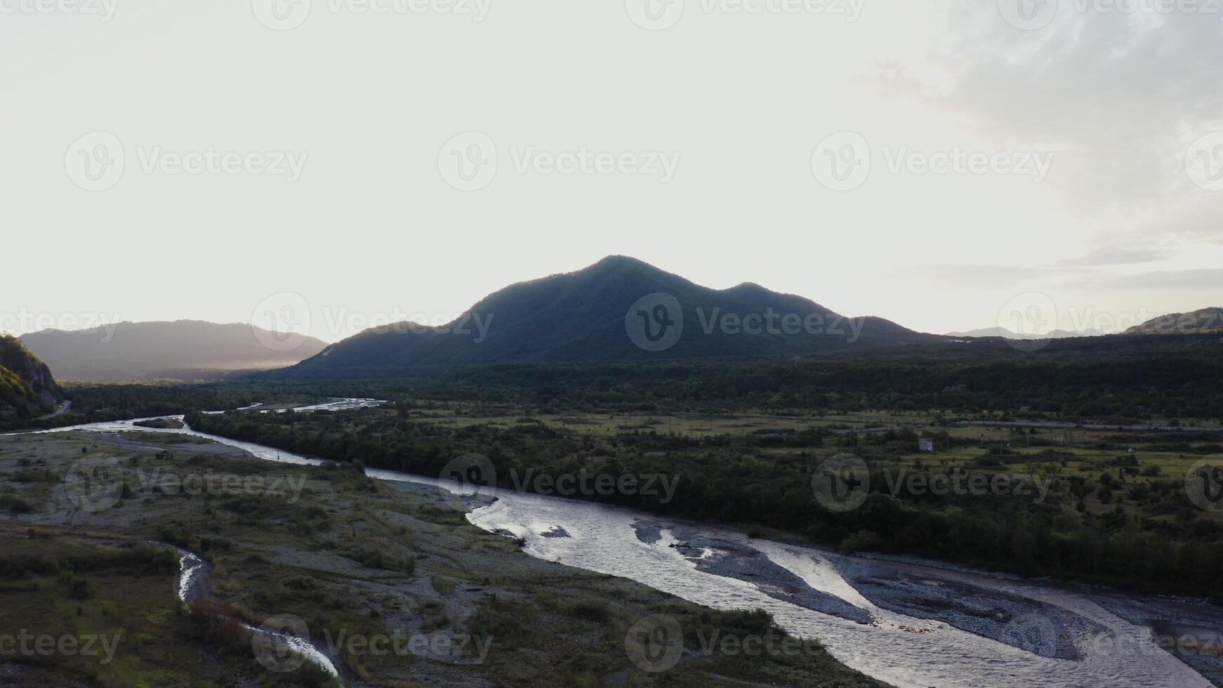 A river runs through a valley with mountains in the background photo
