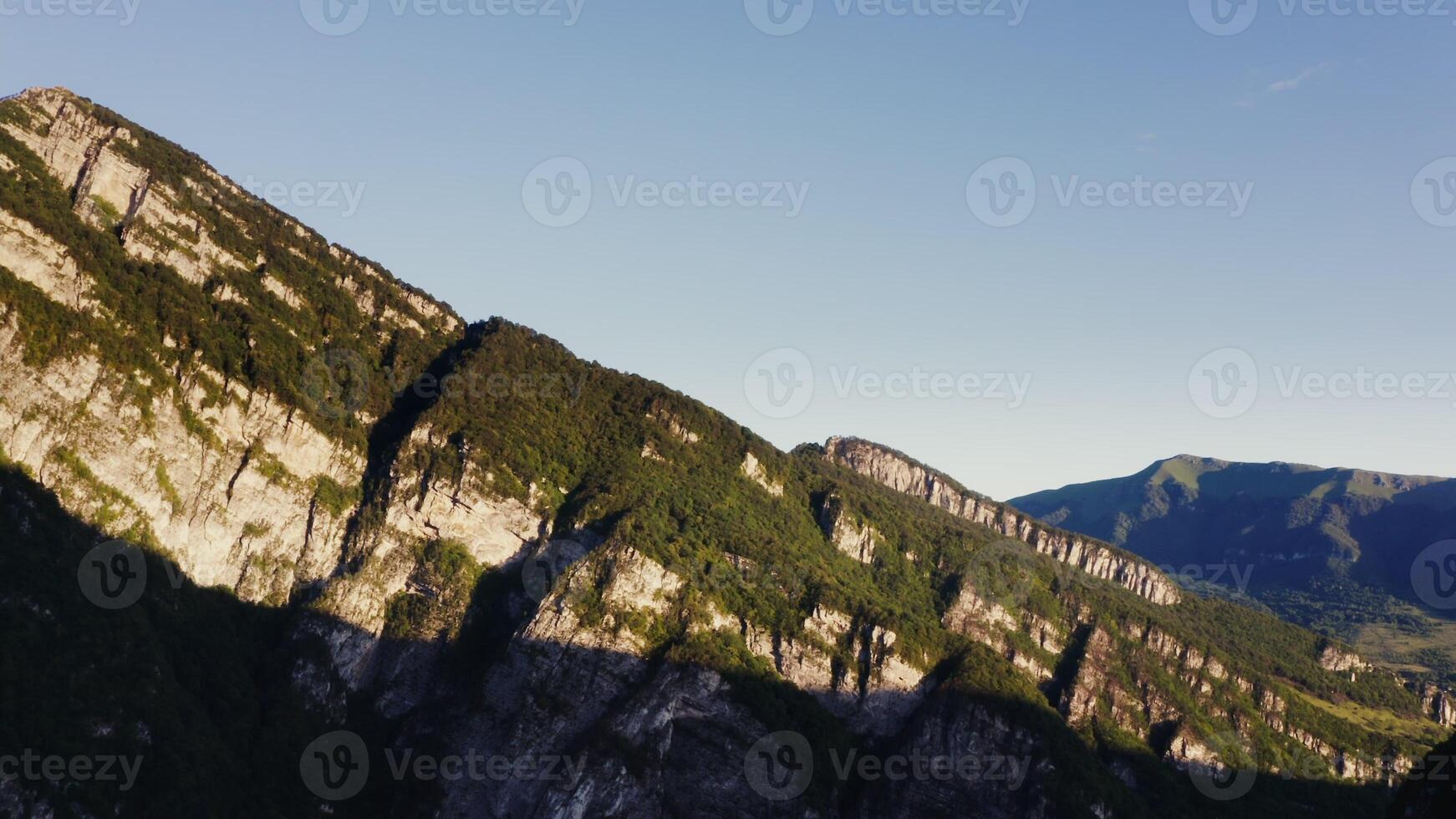 A mountain range with green trees and a blue sky photo