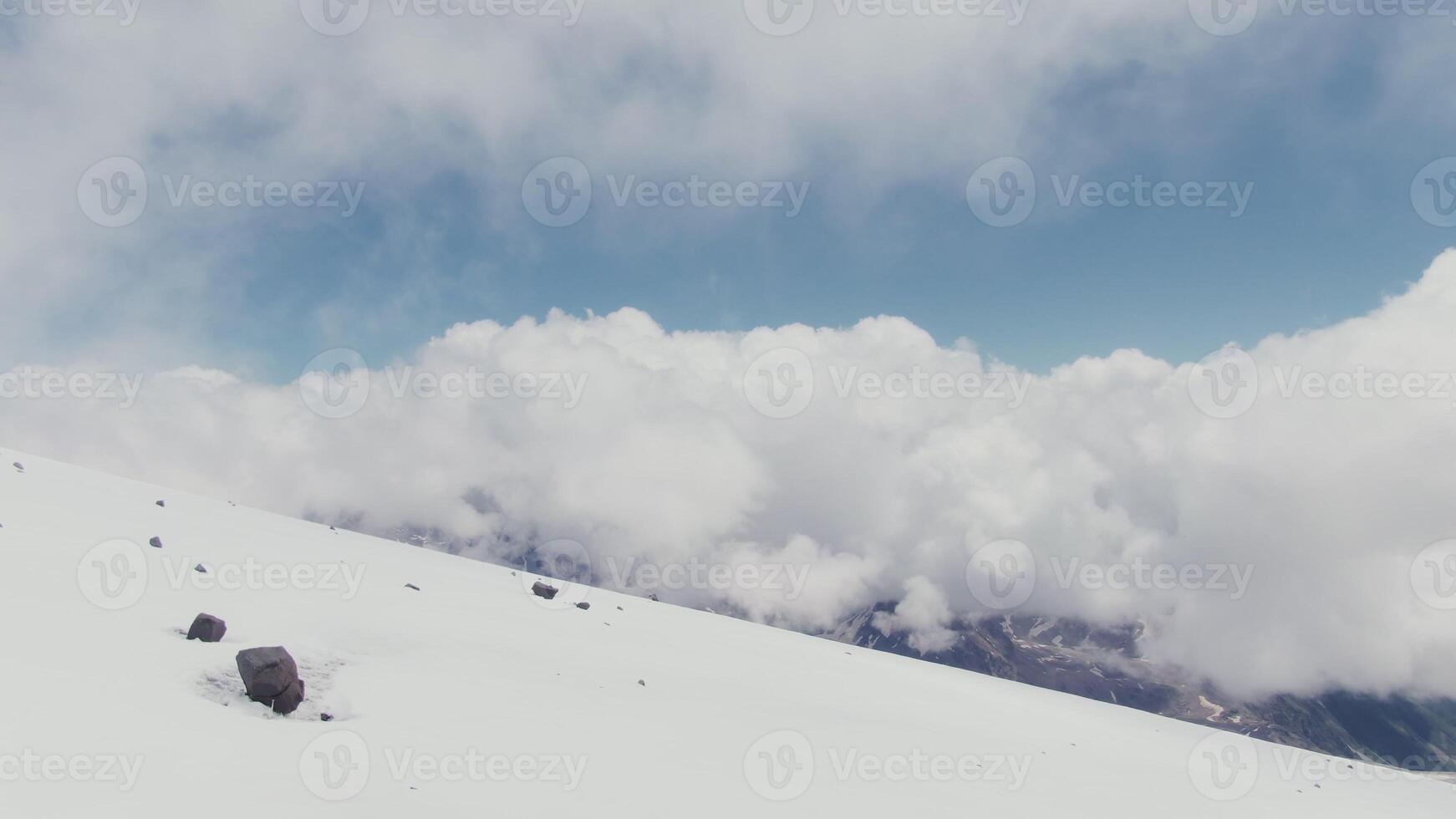 A high-mountainous valley with snow-covered slopes and rocky peaks with clouds photo