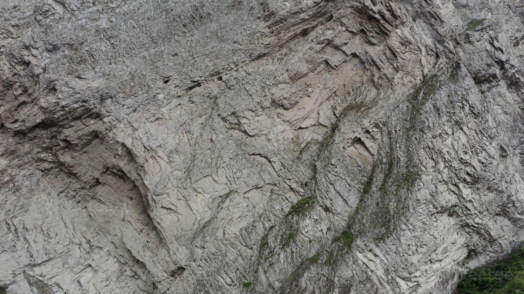 Russia, Caucasus. Aerial from a quadcopter close-up. A slope of rocky mountains with many cracks and chips, overgrown with rare green vegetation photo