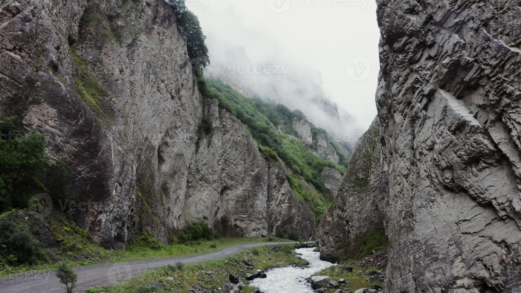 A narrow road running through a canyon with mountains on both sides photo
