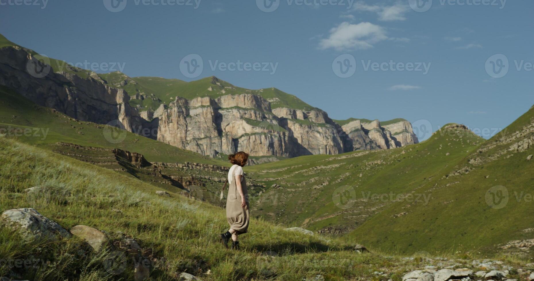 Russia, Caucasus. A young beautiful woman of European appearance descends the hillside and stops on a large steep stone slope photo