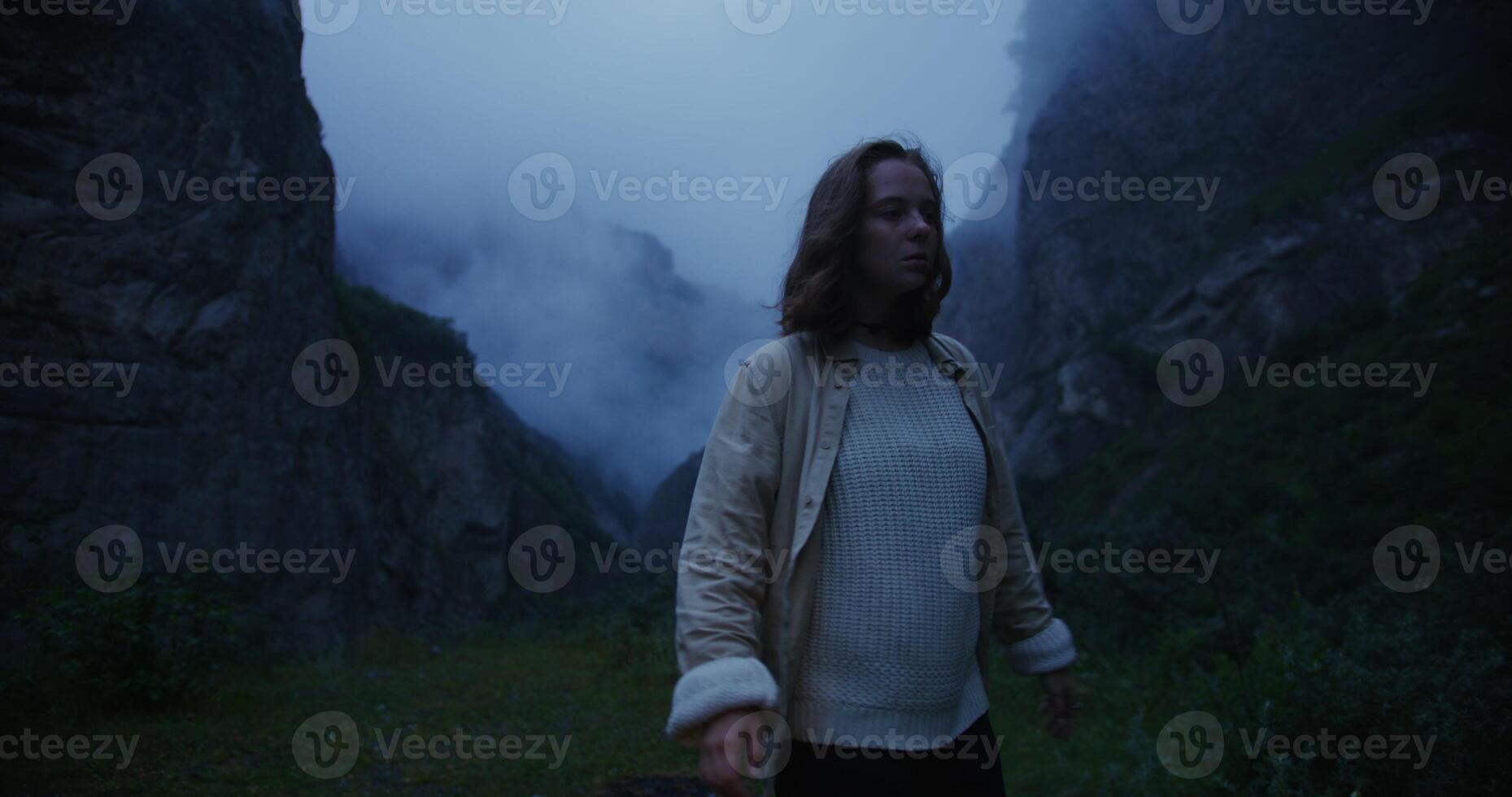 A woman standing in front of a mountain with fog photo