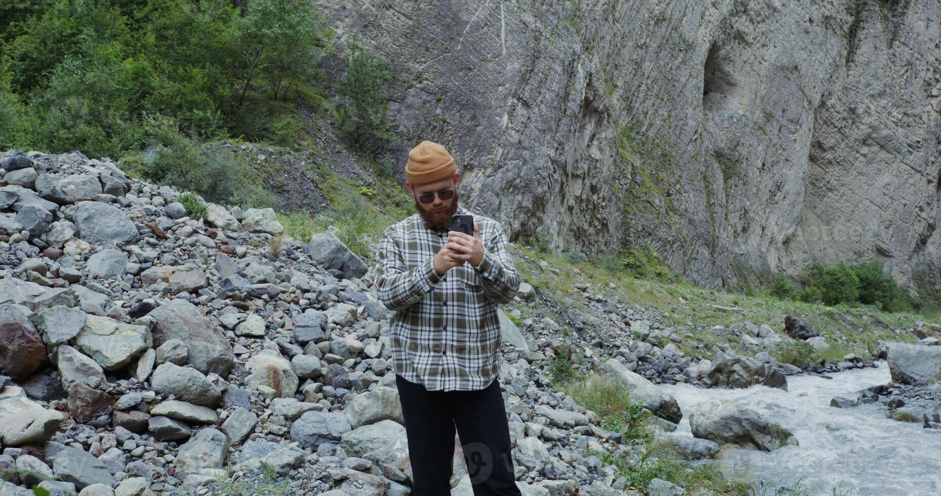 A man in a beanie standing on a rocky hillside photo