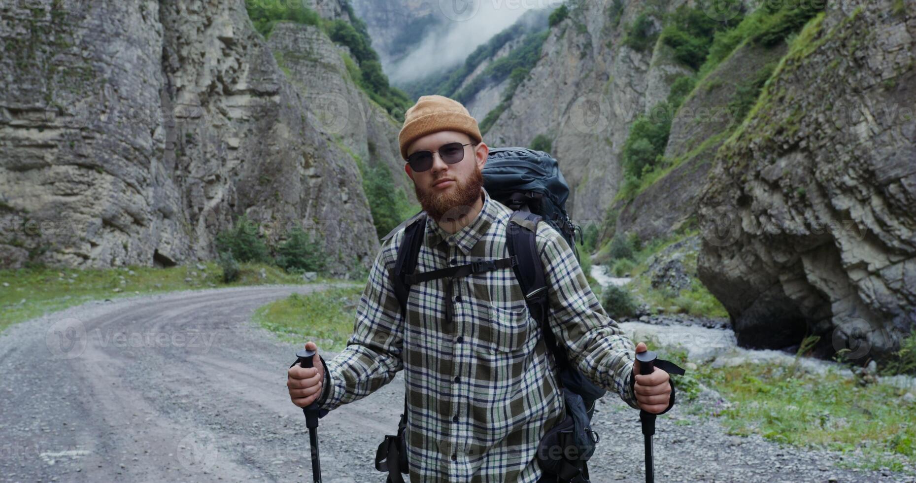 A man with a backpack and hiking poles standing on a road photo