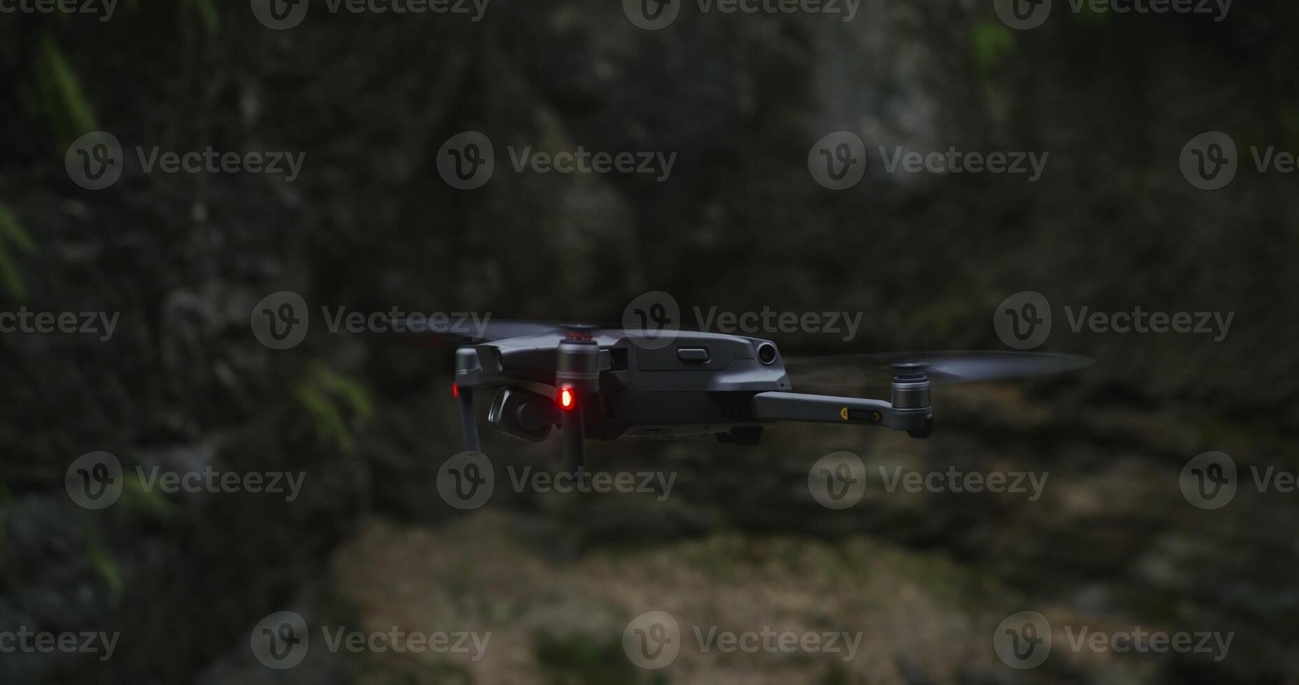A black drone flying over a rocky area photo