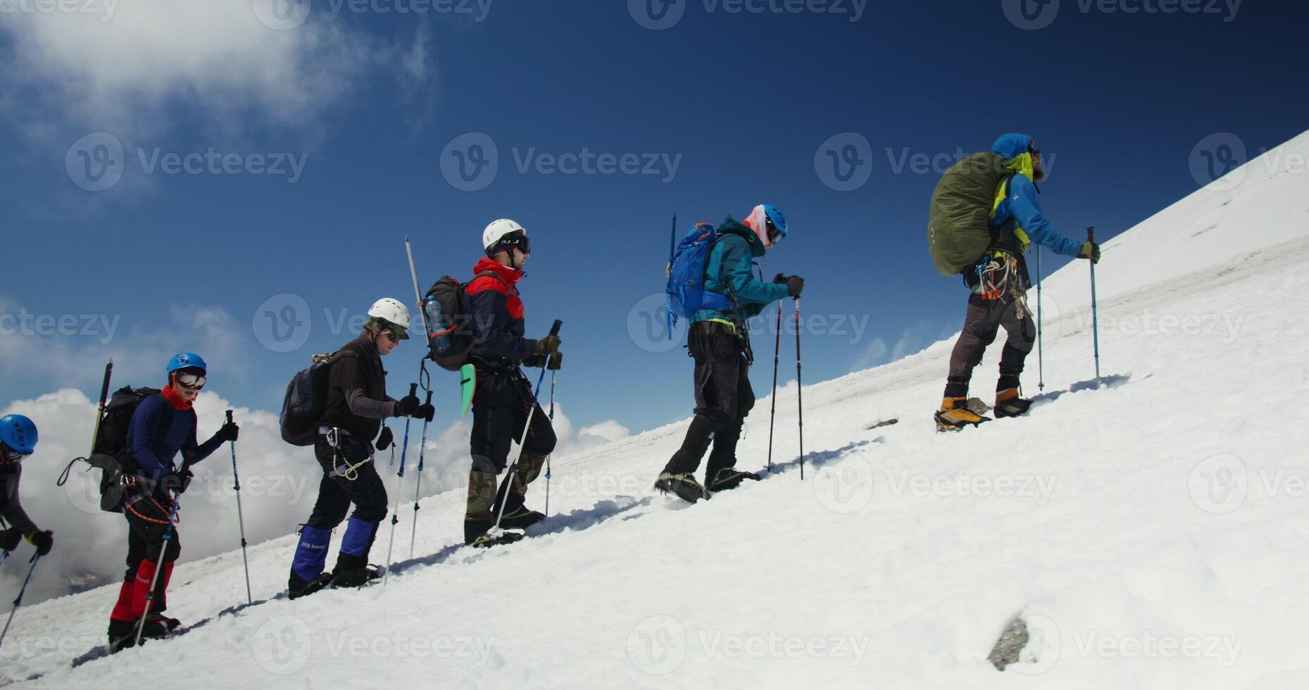 A group of people on skis are climbing up a mountain photo
