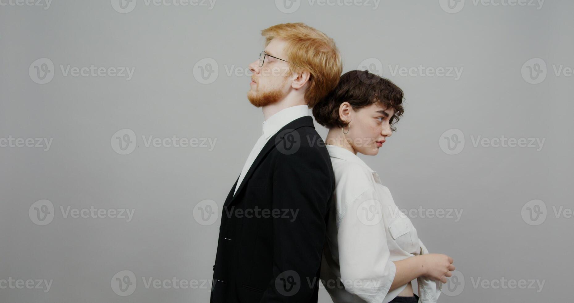The femme fatale is standing back to back with a red-haired businessman dressed in a black business suit. Shooting on a light background photo
