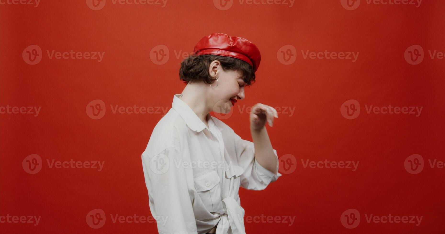A brunette woman of European appearance with a short haircut in a red panama is crying bitterly. Shooting on a red background. photo