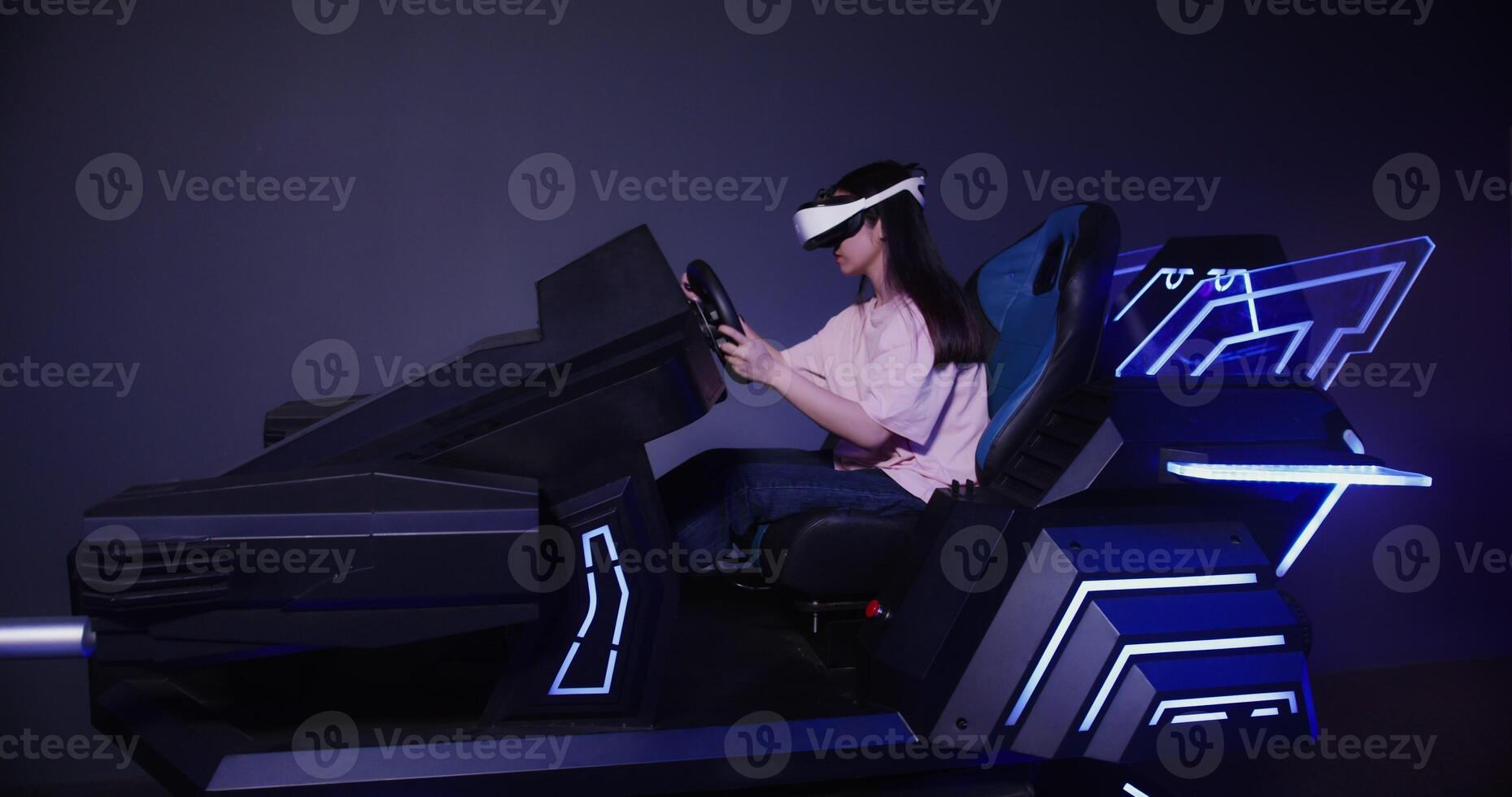 A girl of Asian appearance in virtual reality glasses drives a car in 5D. Virtual simulator for driving training. photo