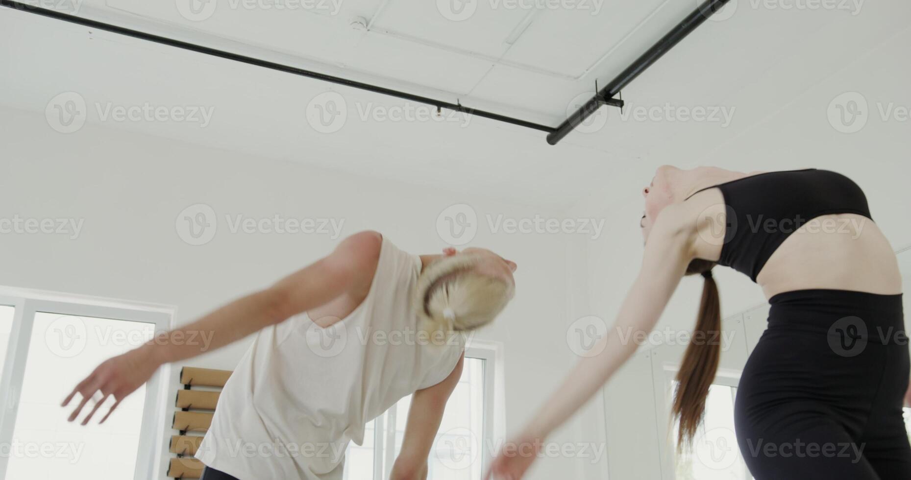 A guy and a girl of European appearance, dressed in sportswear, make synchronized movements while passionately dancing hot dance with each other in a modern gymnastics room photo