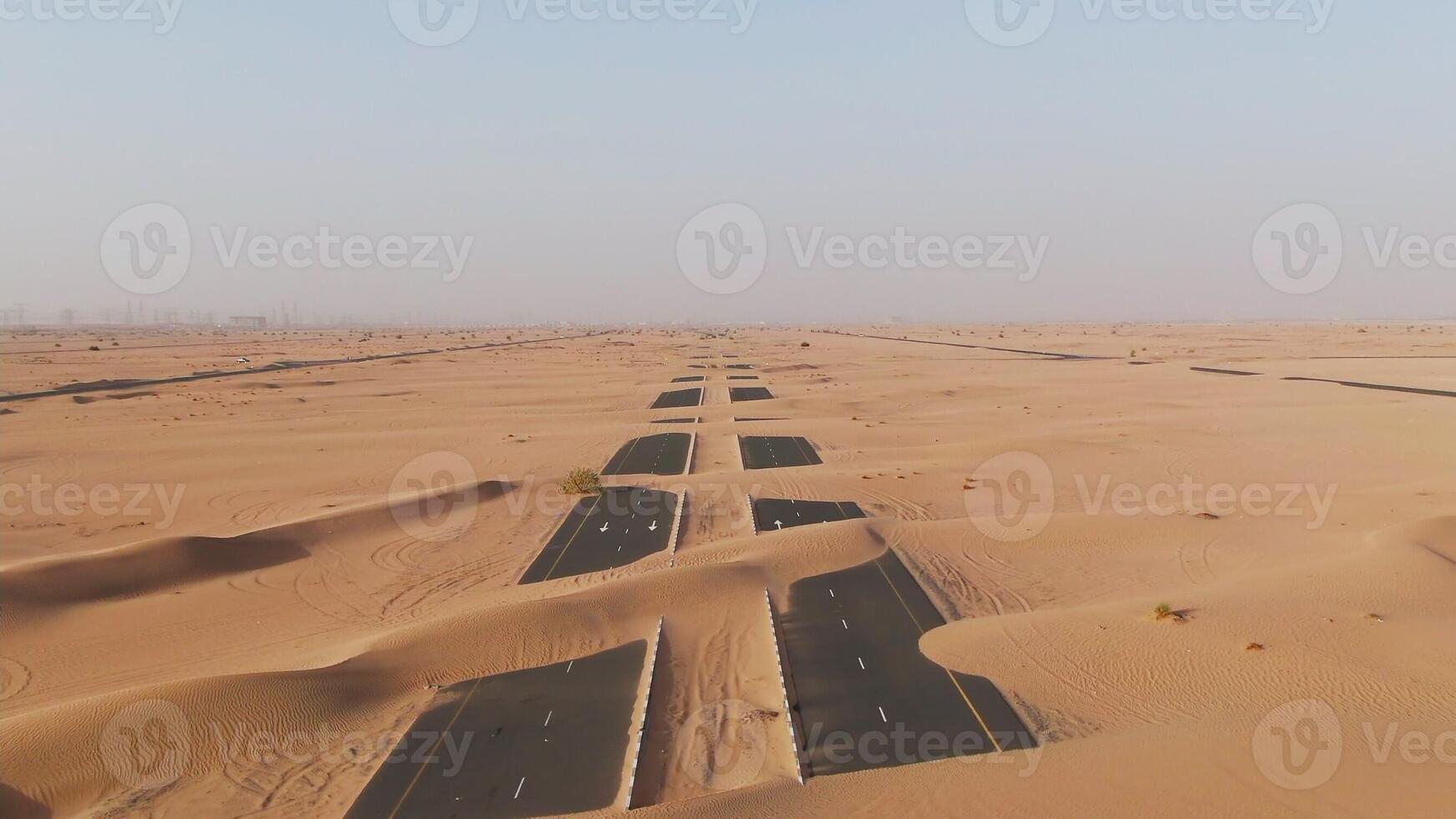 Aerial view of desert paved road buried by sand dunes. Dubai, United Arab Emirates. Daylight drone shooting photo