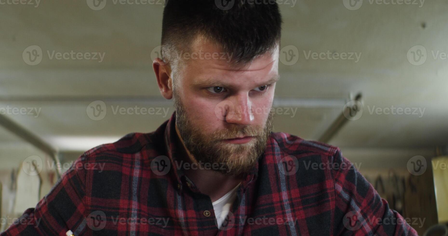 bearded man of European appearance makes notes in the carpentry workshop photo