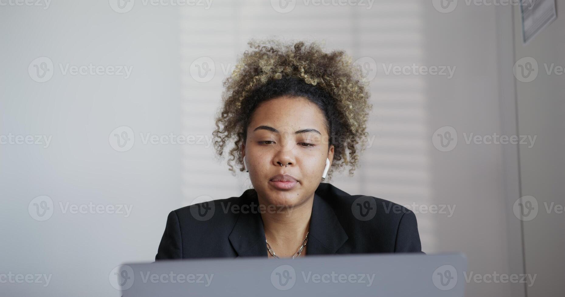 A woman in a business suit sitting at a desk with a laptop photo