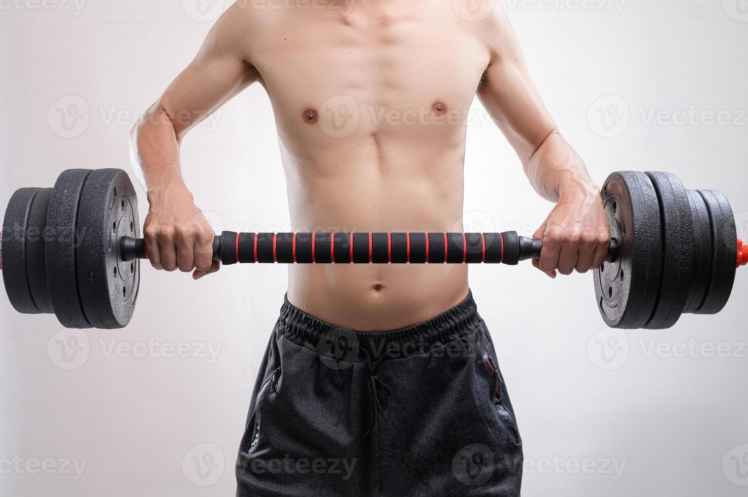 Strong Man Holding Dumbbell in Black Shorts Against Neutral Background photo