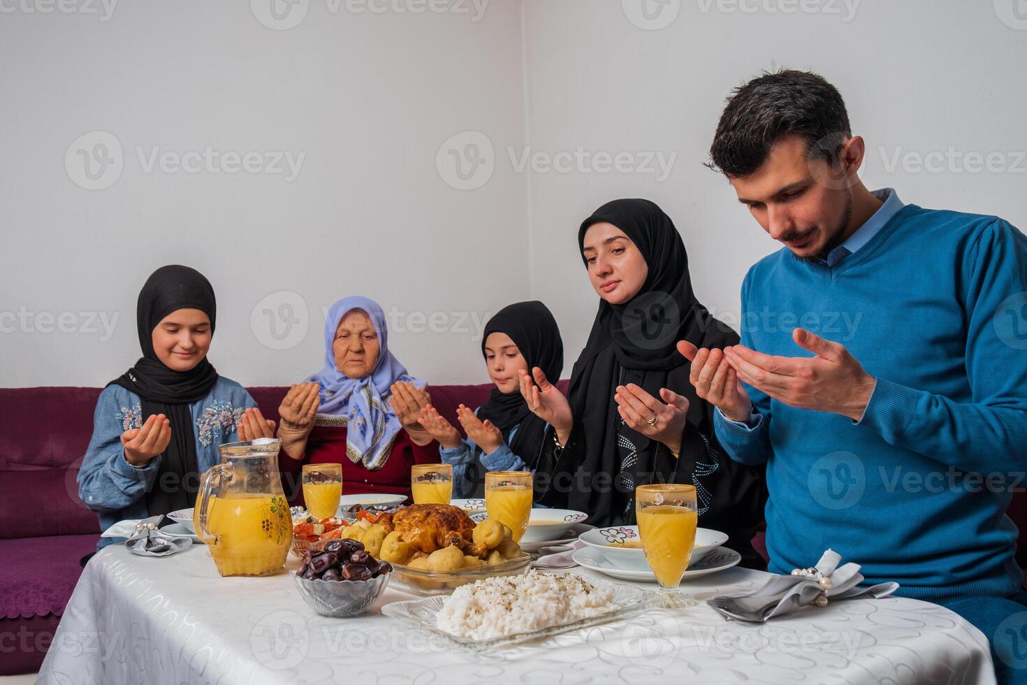 Muslim family making iftar dua to break fasting during Ramadan happy parents having dinner with their children and grandmother at dining table at home. photo