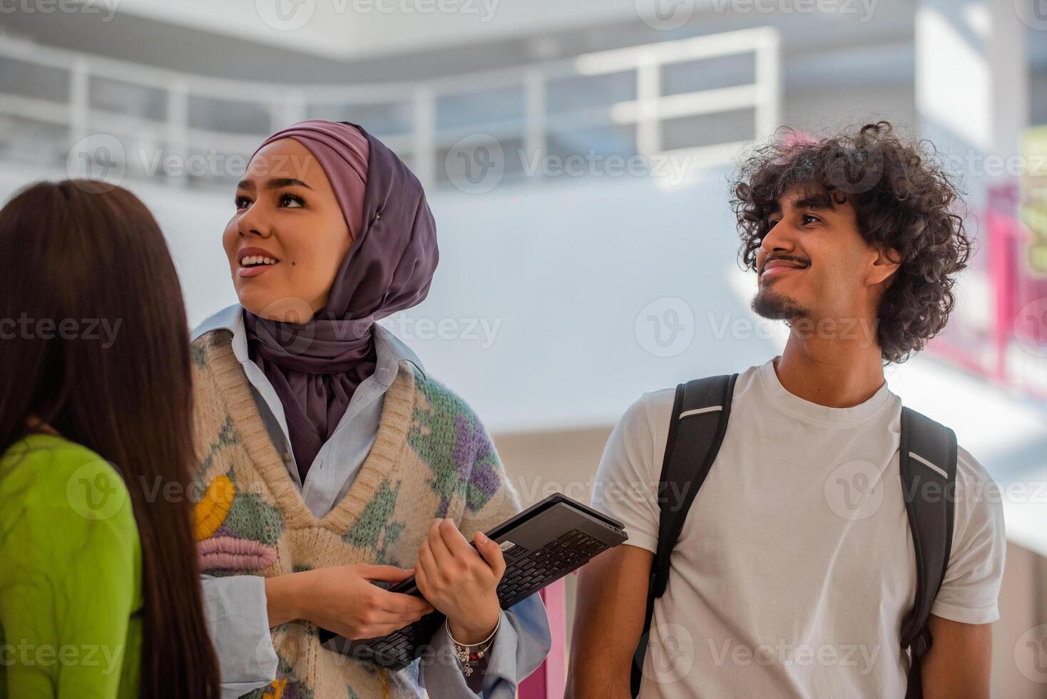 A group of happy diverse college students hanging out they are talking with each other while walking in the university hallway. photo