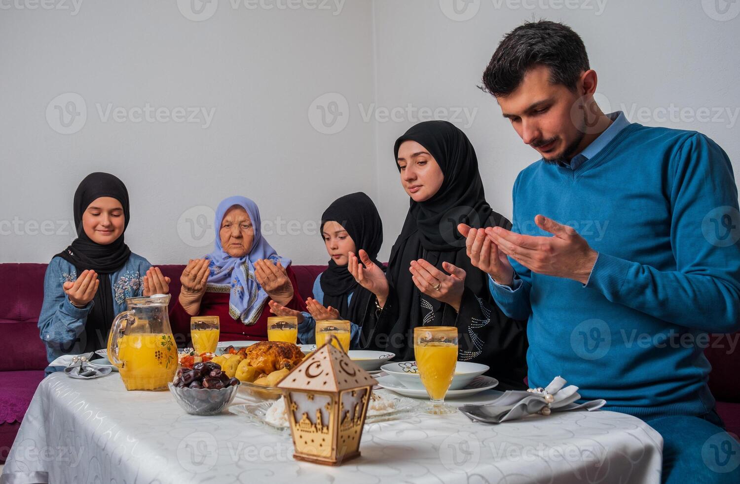 Muslim family making iftar dua to break fasting during Ramadan happy parents having dinner with their children and grandmother at dining table at home. photo