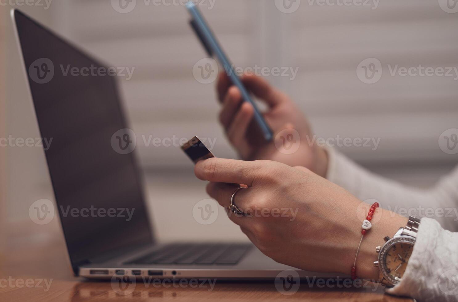 Female hands using mobile phone and holding credit card checking balance or making money transfer. Online Payment Internet Banking Concept. Woman using smartphone for online banking at home close up. photo