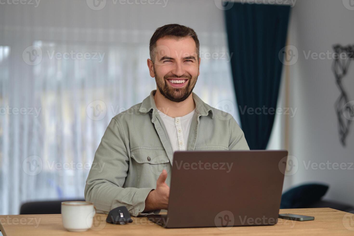 A happy man using a laptop while working at home office. photo