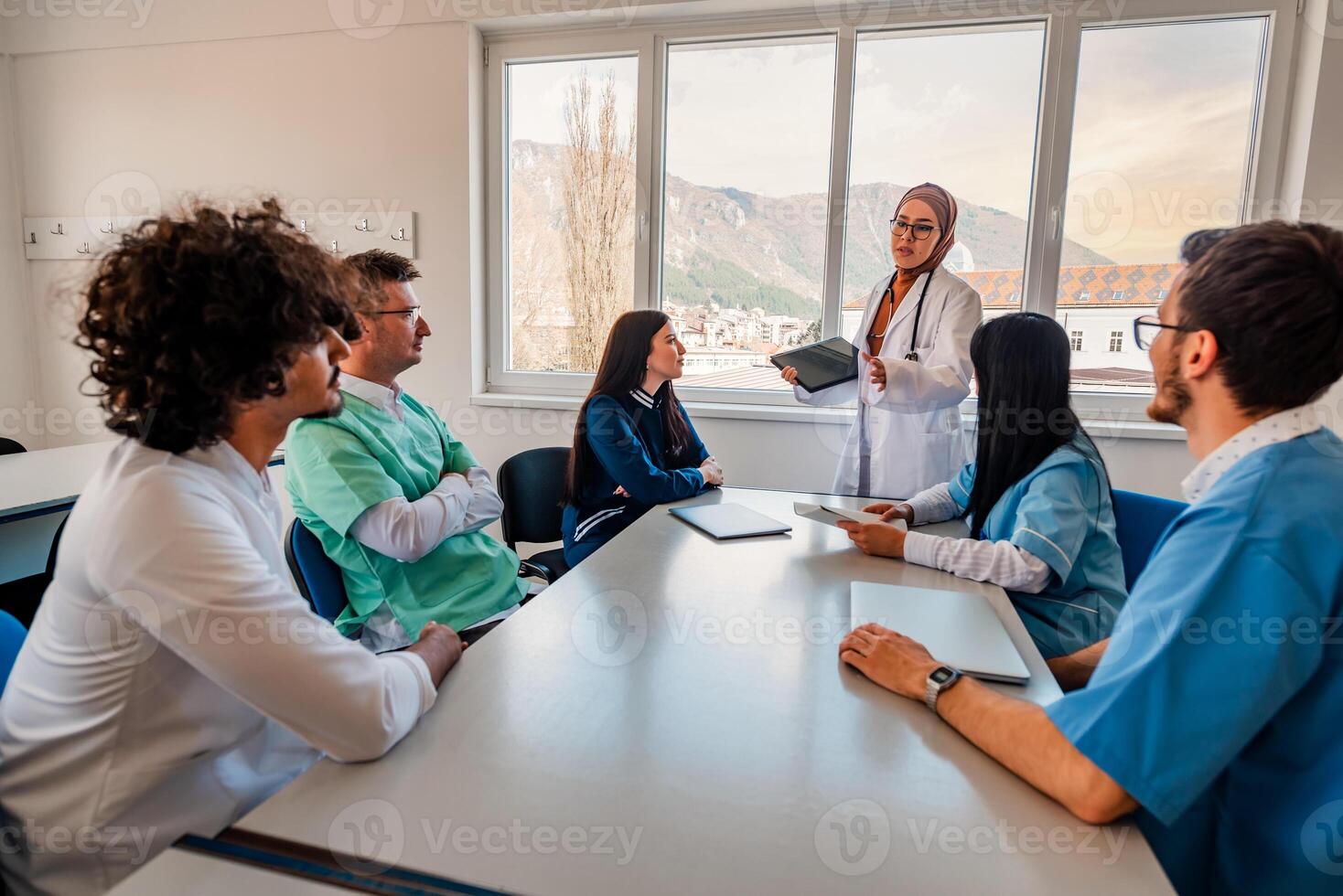 A medical team of doctors discussing at a meeting in the conference room using modern technology. photo
