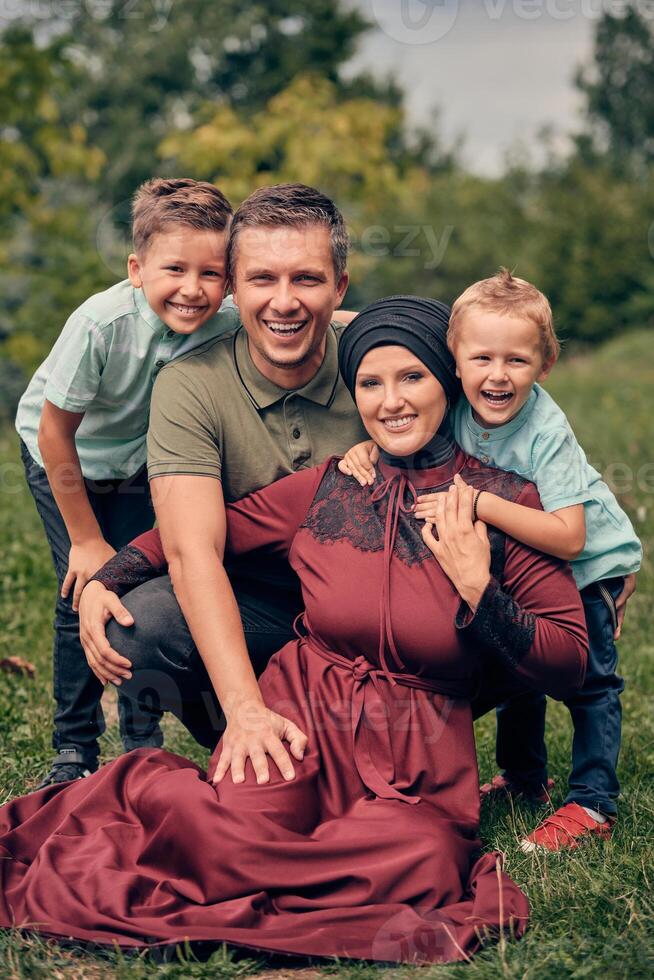 Portrait of a happy Muslim family, young mother and father with two child in the summer park, looking at the camera and smiling.. photo