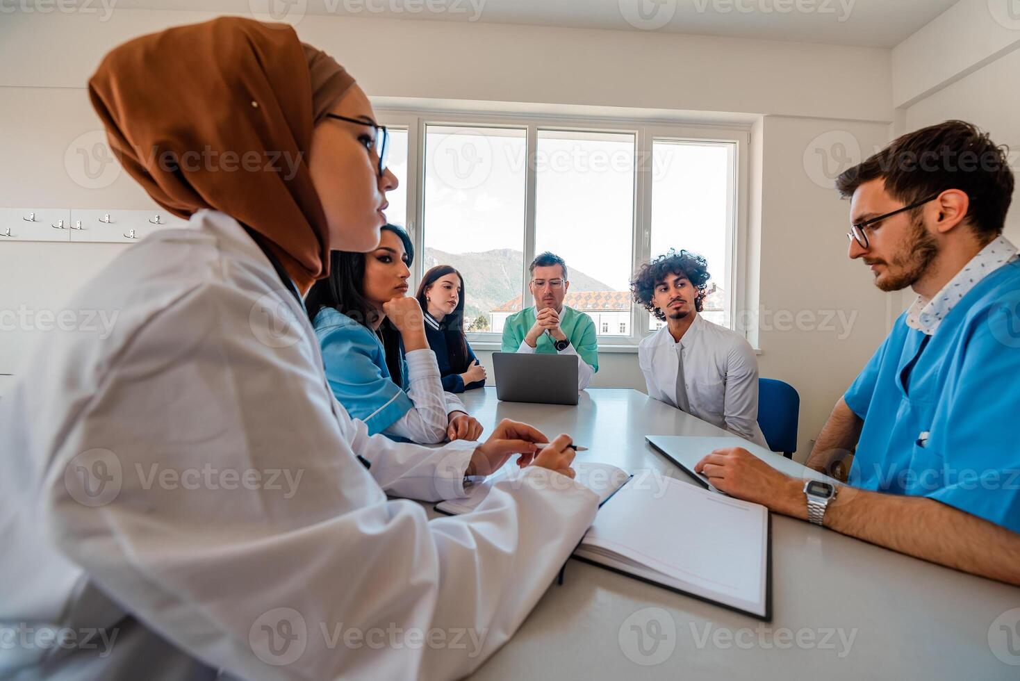 A medical team of doctors discussing at a meeting in the conference room using modern technology. photo