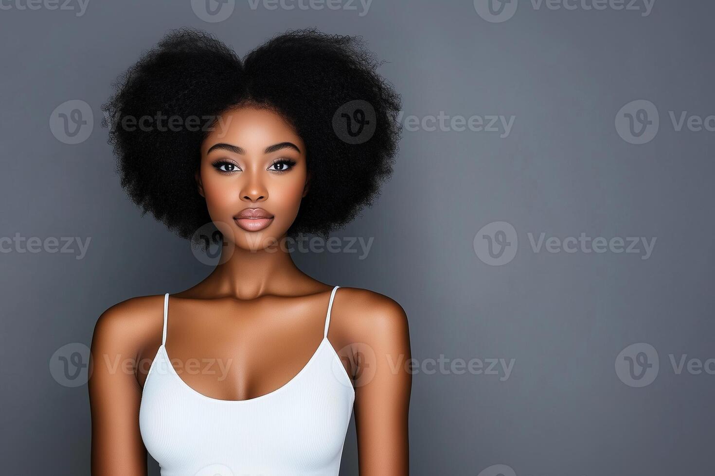 Studio portrait of confident young black woman with afro hairstyle on gray background photo
