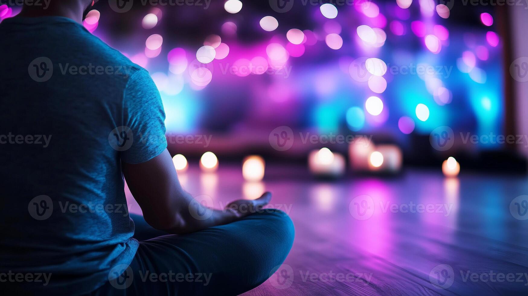 Man meditating in lotus pose with candles and bokeh lights photo