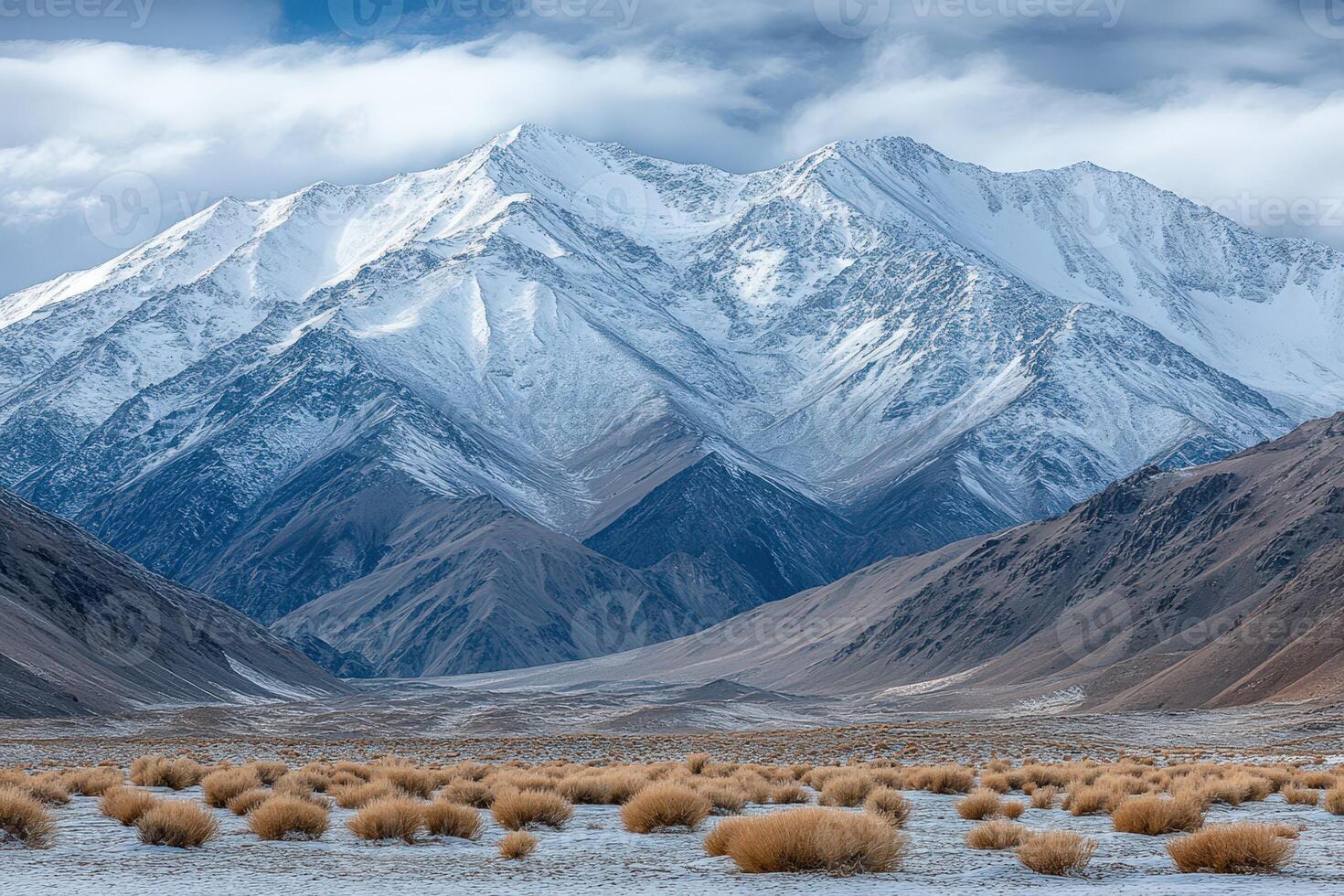 A snowy mountain range with brown grass and snow photo