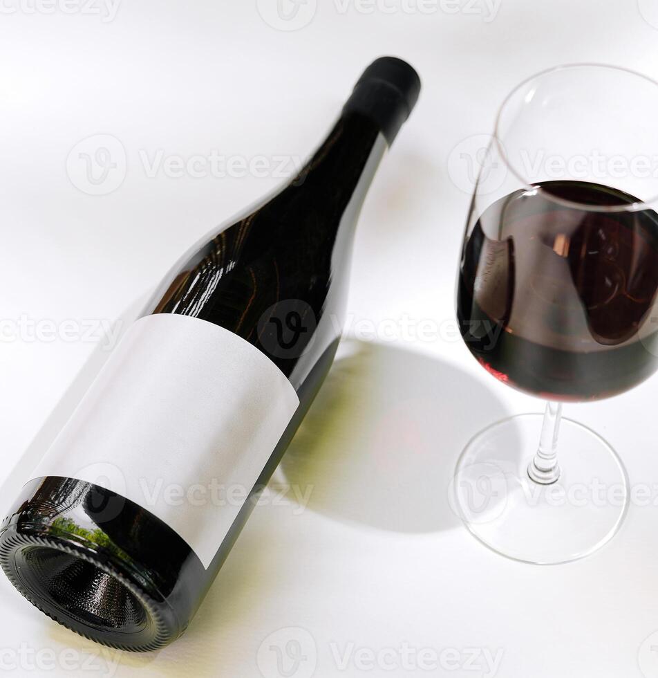 Elegant red wine bottle and glass on a white table photo