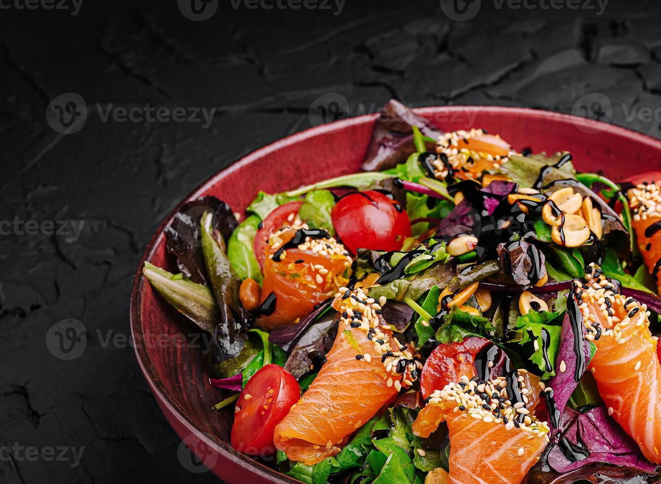 Colorful salad with salmon and fresh vegetables on a dark background photo