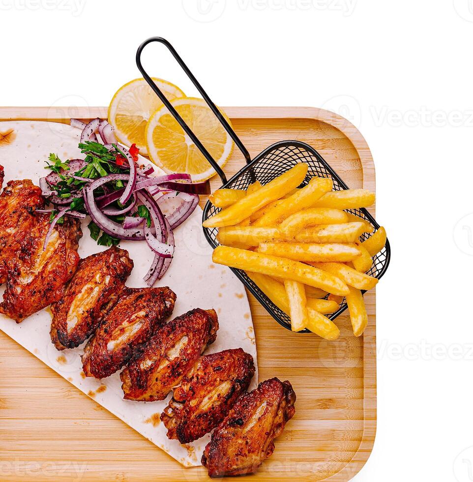 Crispy chicken wings served with fries and fresh lemon slices photo