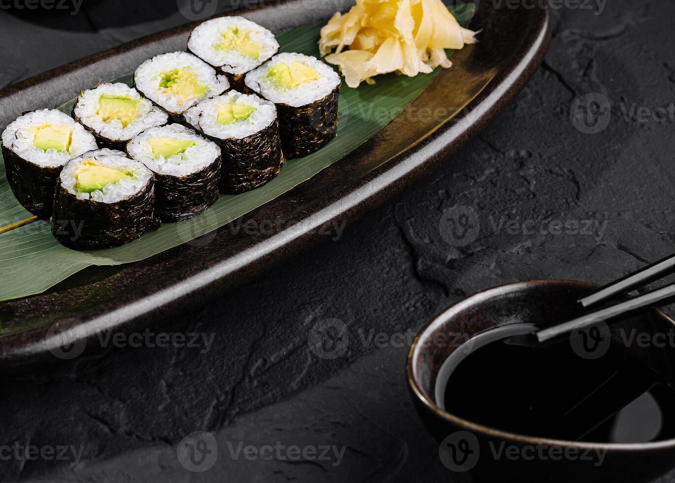 Avocado sushi roll with soy sauce on slate background photo