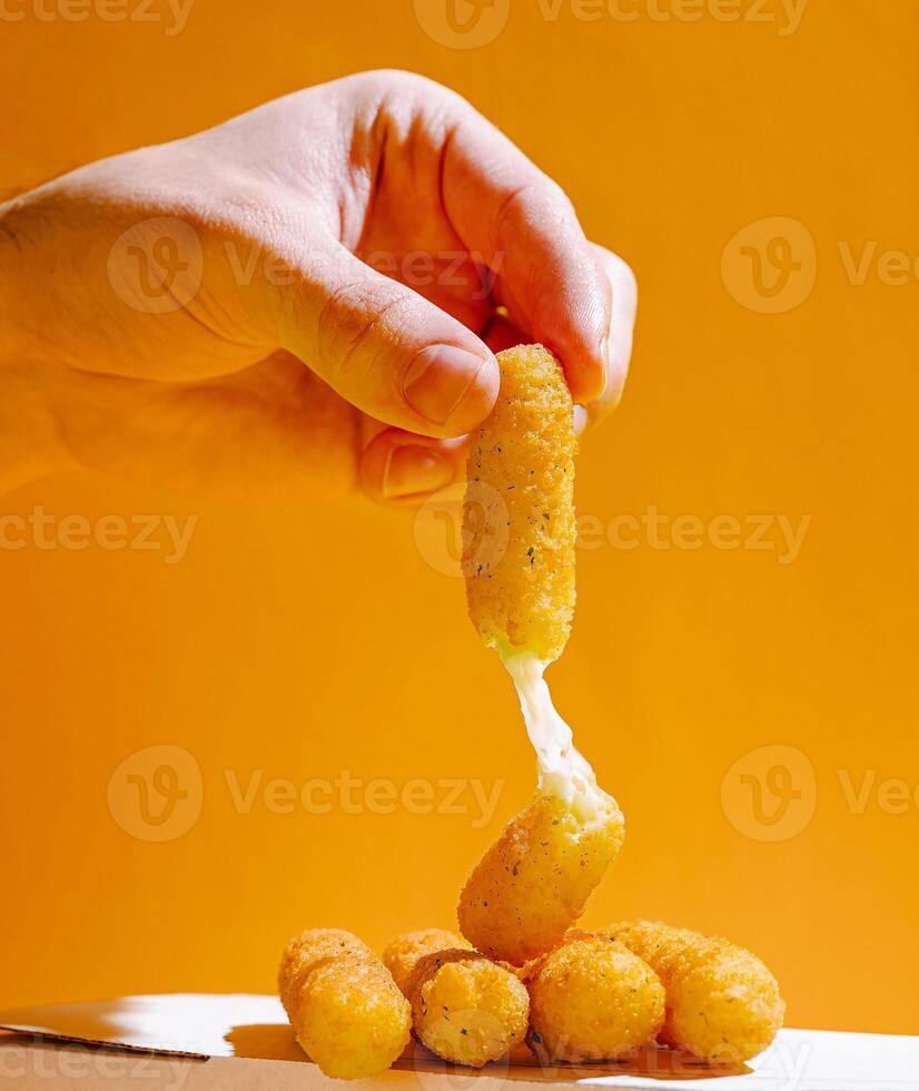 Delicious cheese snack being lifted from a pile on a bright background photo