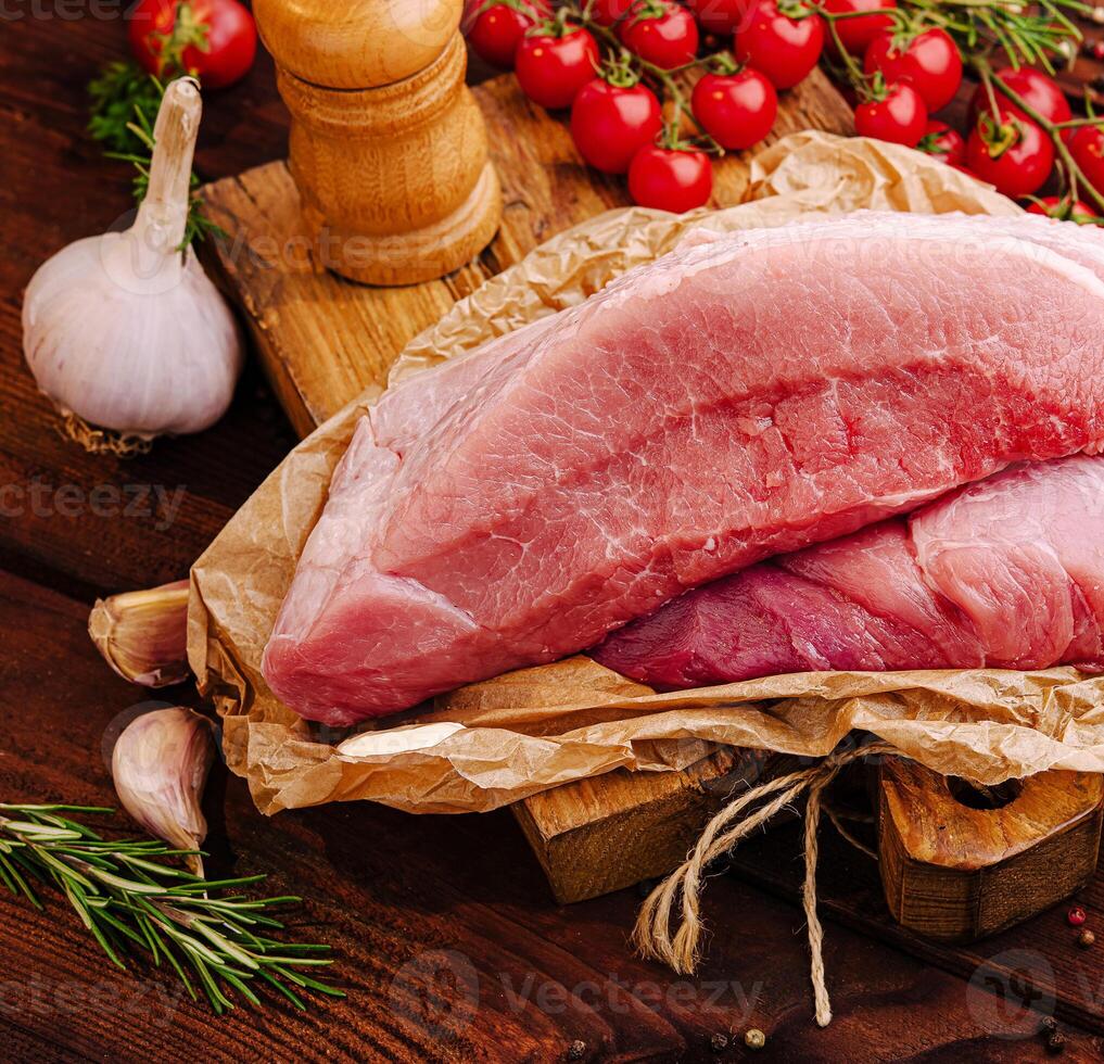 Fresh cut of pork with garlic and cherry tomatoes on wooden board photo