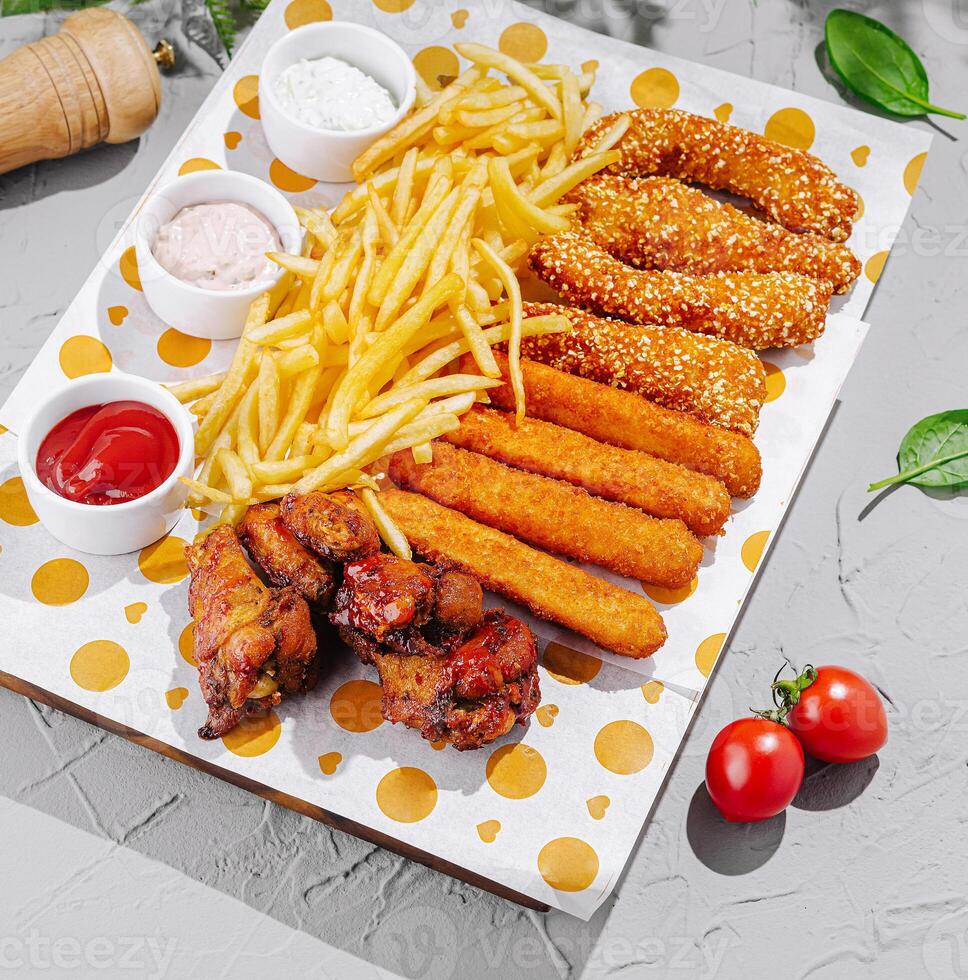 Tasty platter of fried snacks with dipping sauces and fries photo