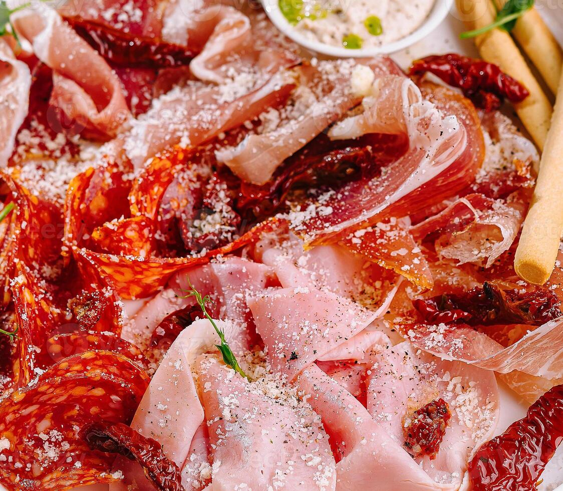 Assorted deli meats platter with dips and breadsticks closeup photo