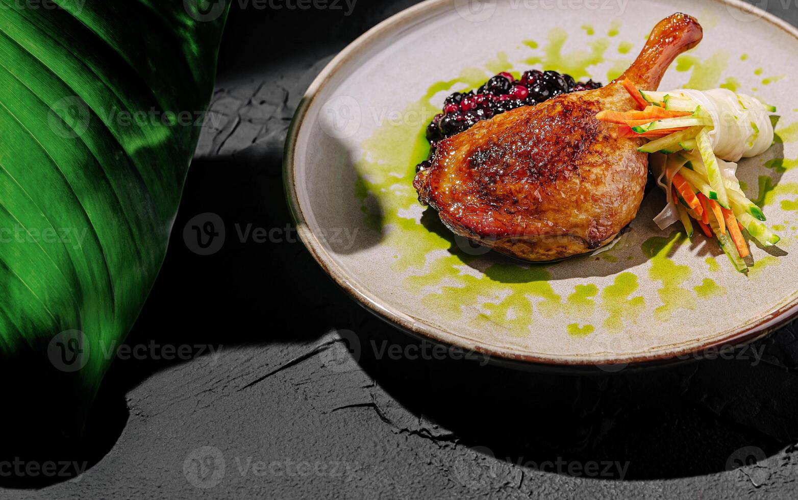 Crispy duck leg served with berry sauce and fresh vegetables photo