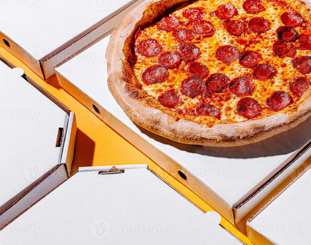 Freshly baked pepperoni pizza with empty boxes on a table photo