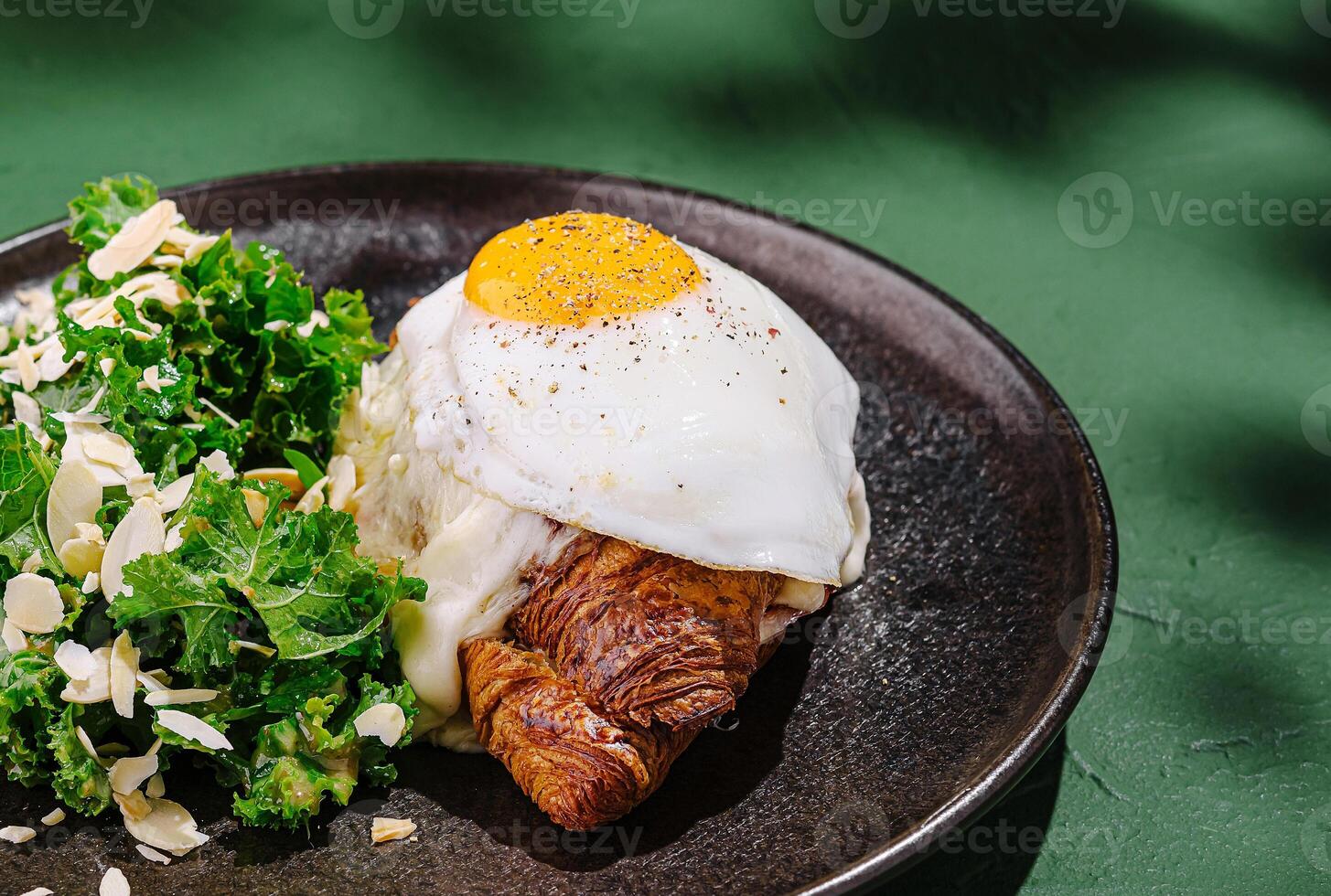 Delicious croissant topped with fried egg and greens on plate photo