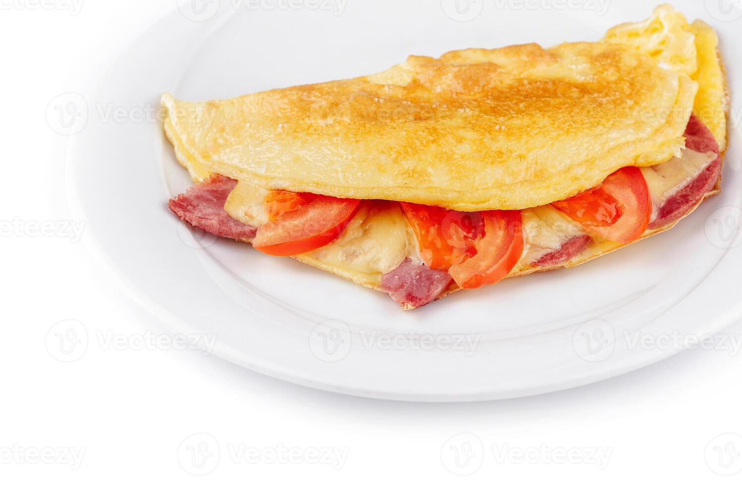 Folded omelette filled with cheese, ham and tomatoes on white plate close up photo
