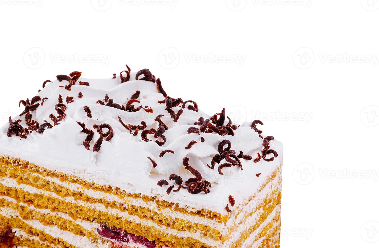 Delicious honey cake decorated with whipped cream and chocolate shavings close up photo