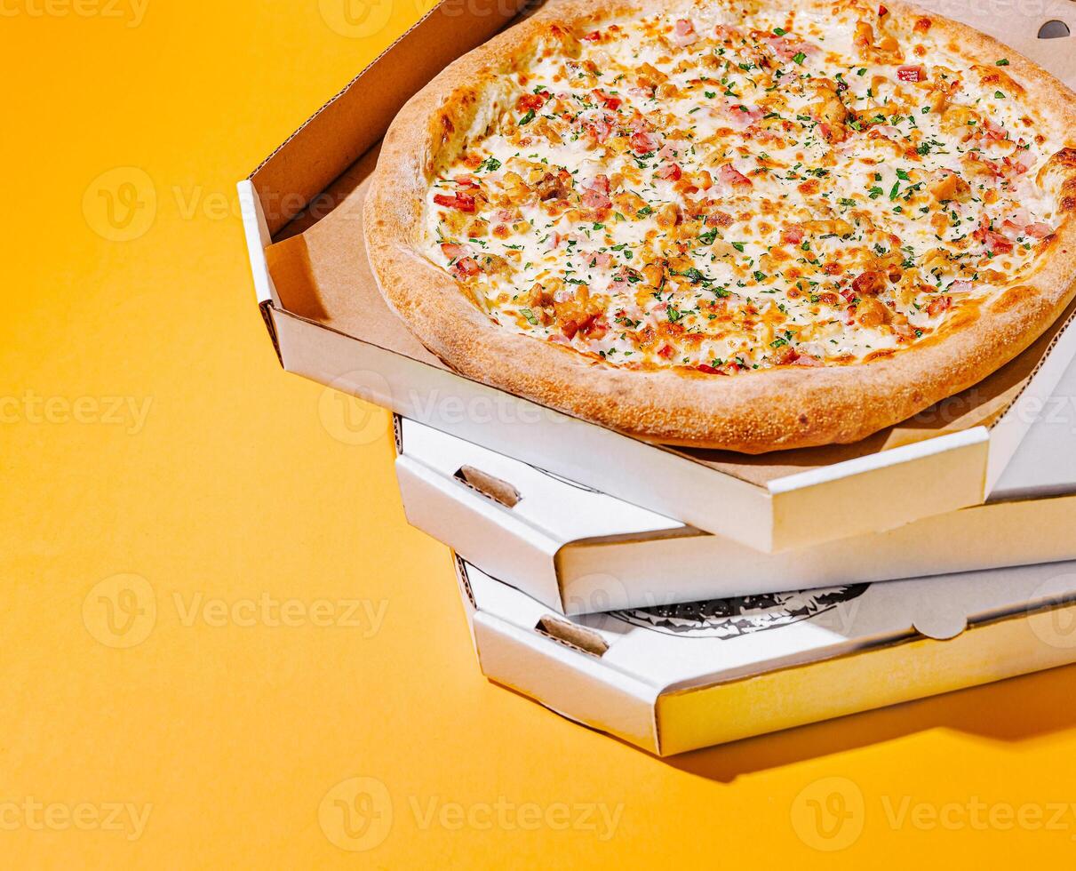 Freshly baked pizza in vibrant yellow setting with boxes photo