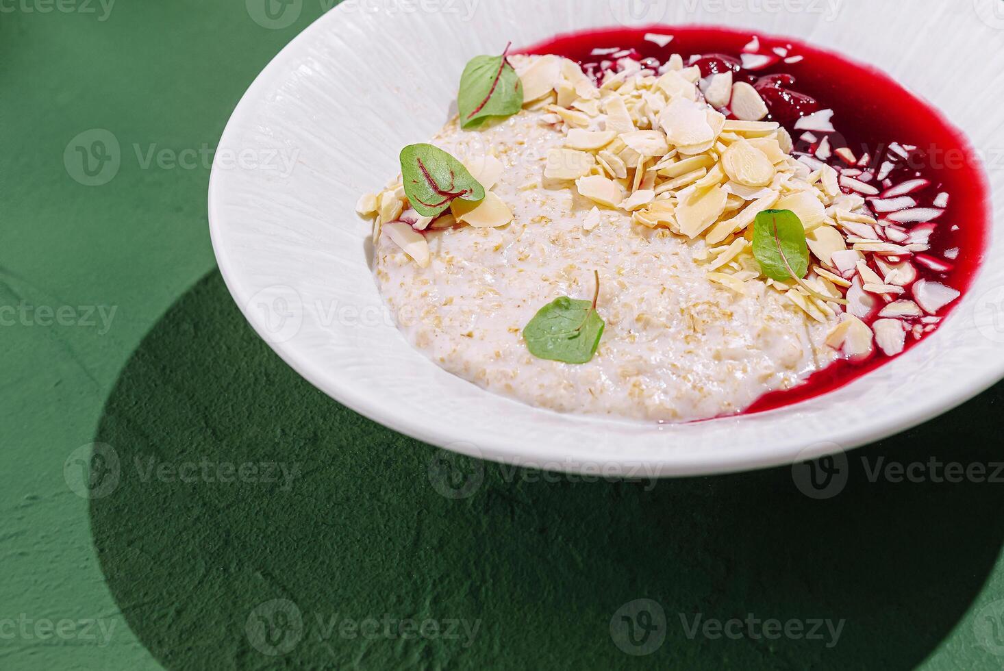 Delicious oatmeal bowl topped with berry sauce and almonds photo